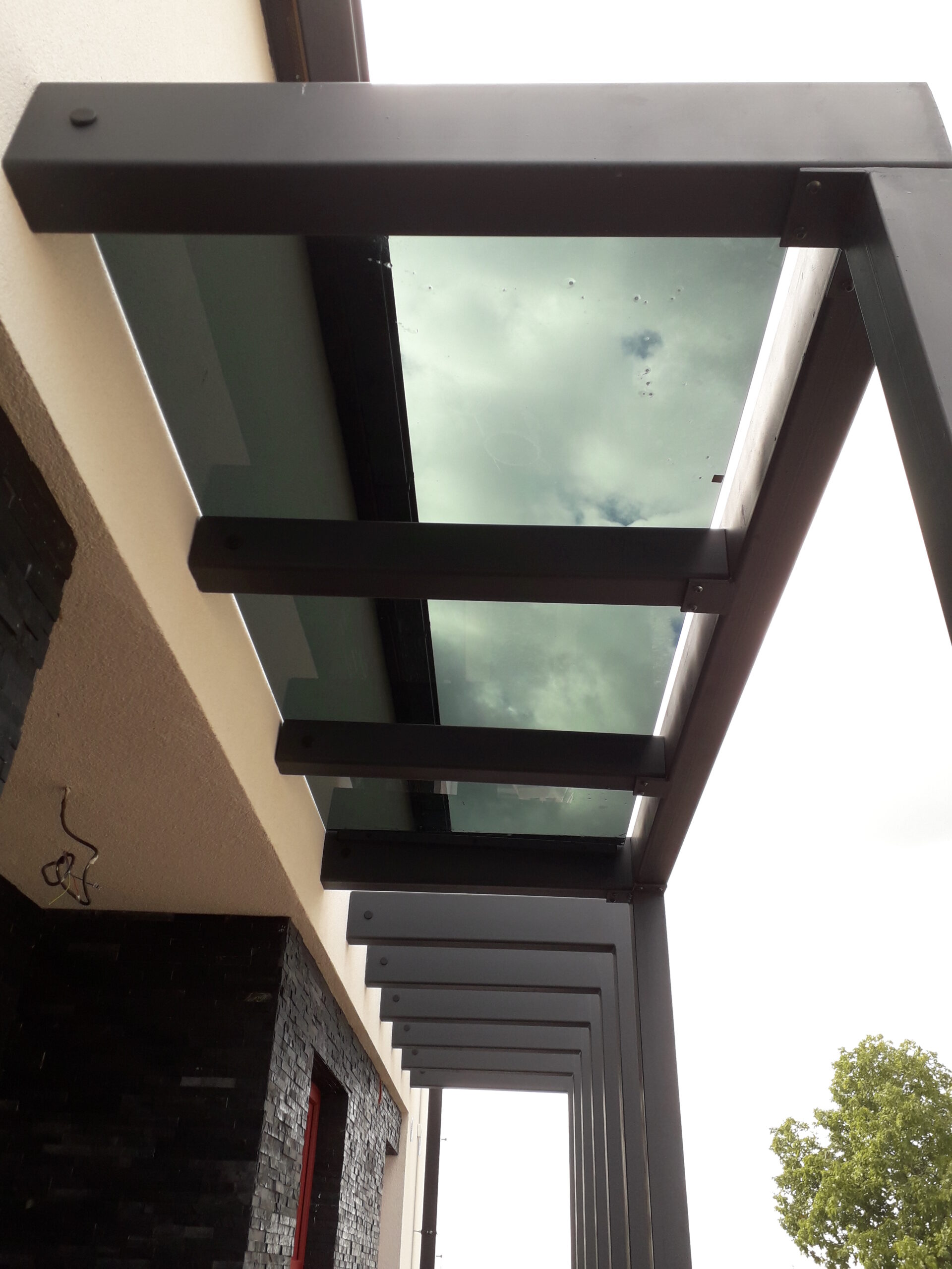 Prosklená střecha s kovovou konstrukcí, chránící vstup do domu